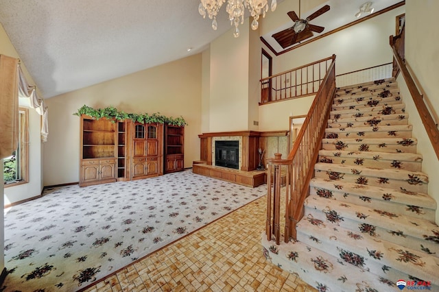 living room with a textured ceiling, ceiling fan, a fireplace, and high vaulted ceiling