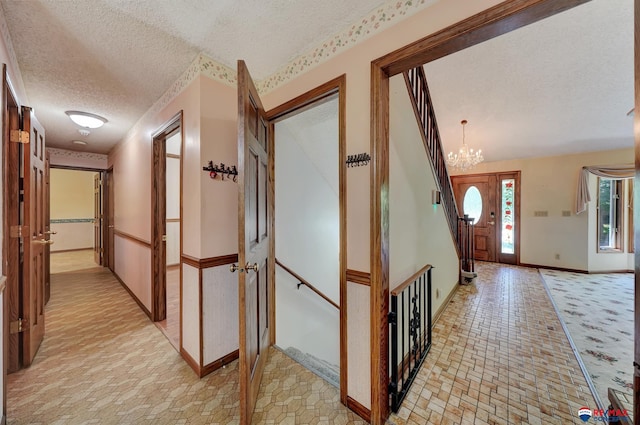 hallway featuring a textured ceiling and an inviting chandelier