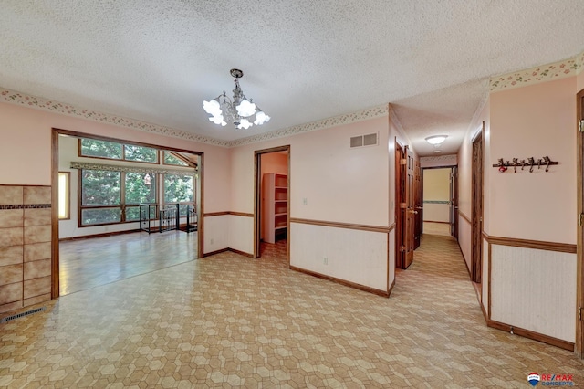 unfurnished room with a chandelier and a textured ceiling