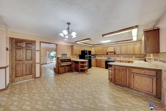 kitchen with a textured ceiling, sink, black appliances, pendant lighting, and a chandelier