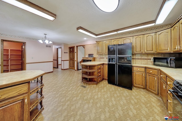 kitchen featuring black appliances, pendant lighting, a textured ceiling, and an inviting chandelier