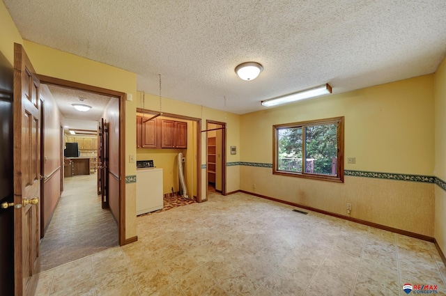 kitchen with washing machine and clothes dryer and a textured ceiling