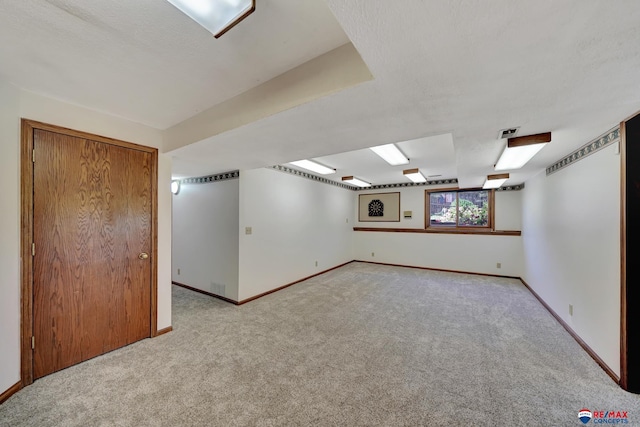 basement featuring light carpet and a textured ceiling