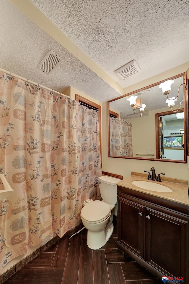 bathroom with vanity, toilet, a textured ceiling, and an inviting chandelier