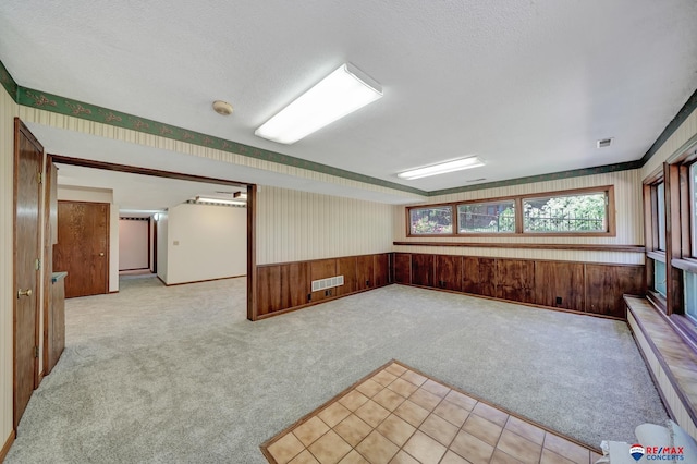 spare room with wood walls, light colored carpet, and a textured ceiling