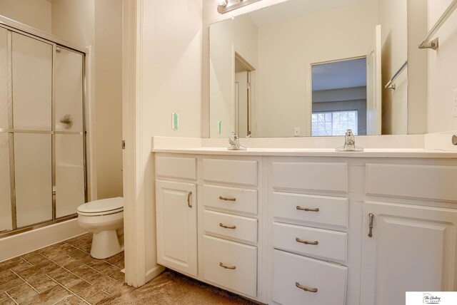 bathroom featuring vanity, toilet, and a shower with shower door