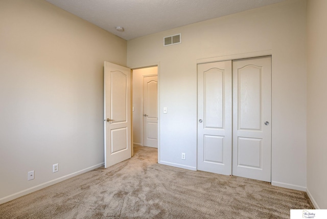 unfurnished bedroom with a closet and light colored carpet