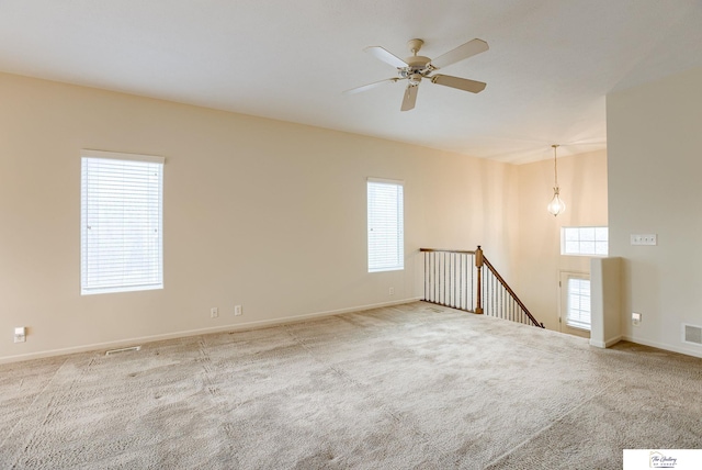 carpeted spare room featuring ceiling fan and a healthy amount of sunlight