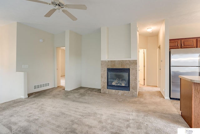 unfurnished living room with light carpet, a fireplace, and ceiling fan