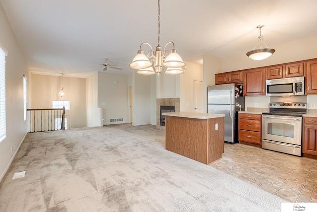 kitchen with appliances with stainless steel finishes, ceiling fan with notable chandelier, a kitchen island, and hanging light fixtures