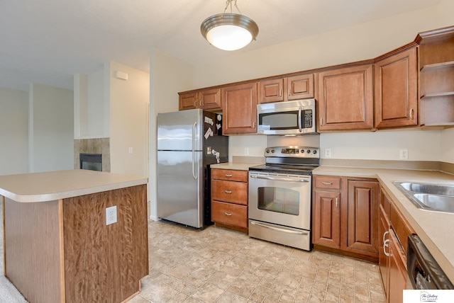 kitchen featuring a fireplace, a kitchen island, sink, and stainless steel appliances