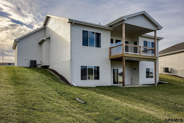 rear view of house with a lawn, central AC, and a balcony