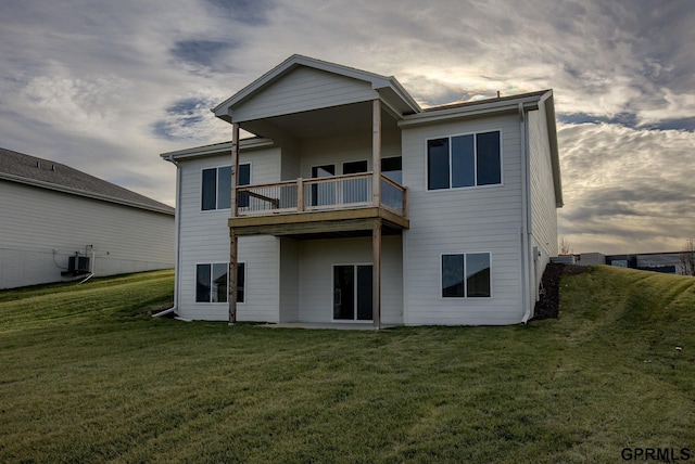 back house at dusk with a yard, a balcony, and cooling unit