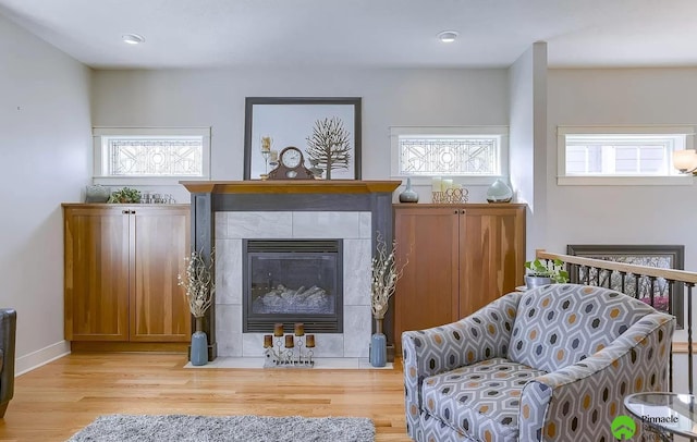 living area with a tiled fireplace and light wood-type flooring