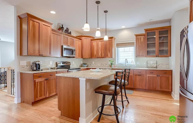 kitchen with a breakfast bar, a center island, light hardwood / wood-style floors, and appliances with stainless steel finishes