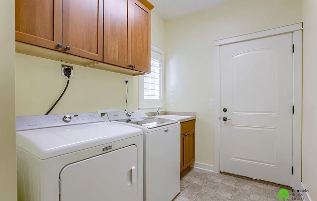 clothes washing area with cabinets, sink, and washing machine and clothes dryer