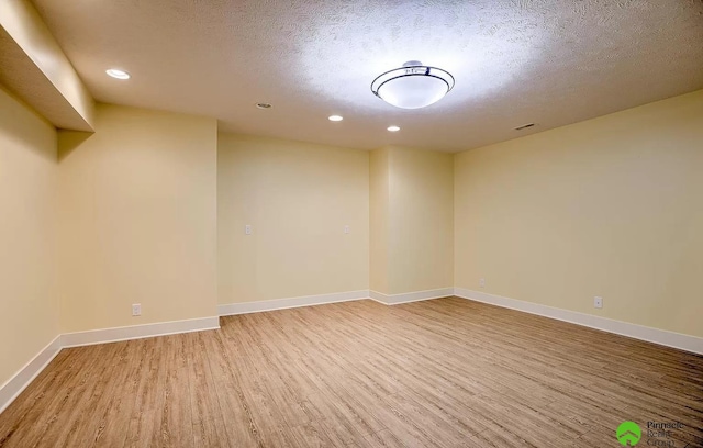 spare room with a textured ceiling and light wood-type flooring