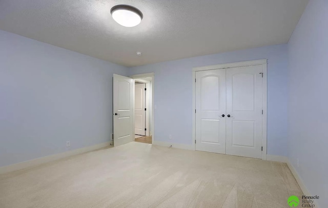 unfurnished bedroom with light colored carpet, a textured ceiling, and a closet