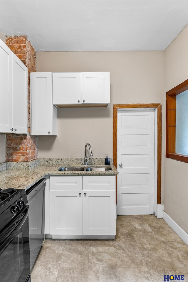 kitchen featuring black appliances, light stone countertops, white cabinetry, and sink