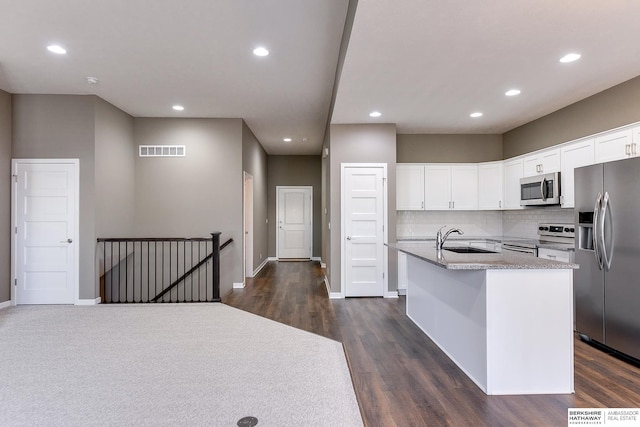 kitchen with white cabinetry, sink, stainless steel appliances, dark hardwood / wood-style floors, and an island with sink