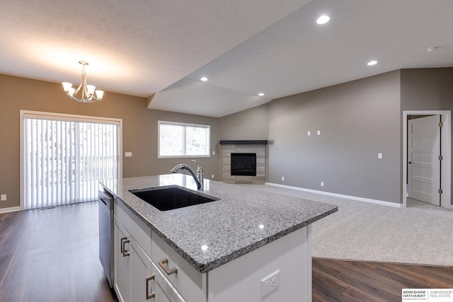 kitchen with dark wood-type flooring, white cabinets, sink, hanging light fixtures, and light stone counters