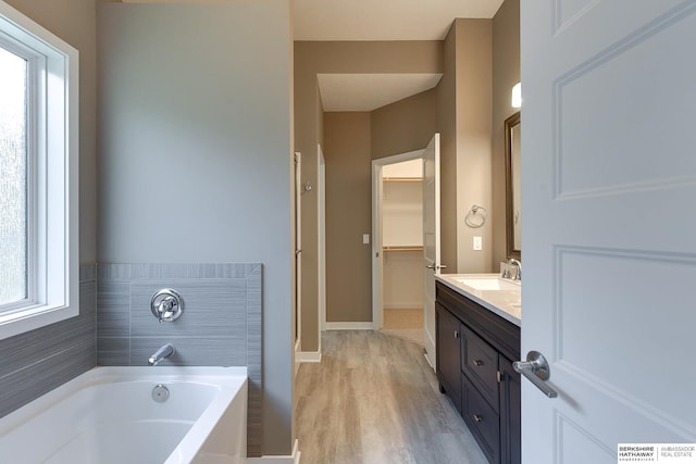 bathroom with a tub, plenty of natural light, vanity, and wood-type flooring