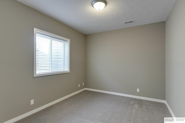 carpeted empty room featuring a textured ceiling