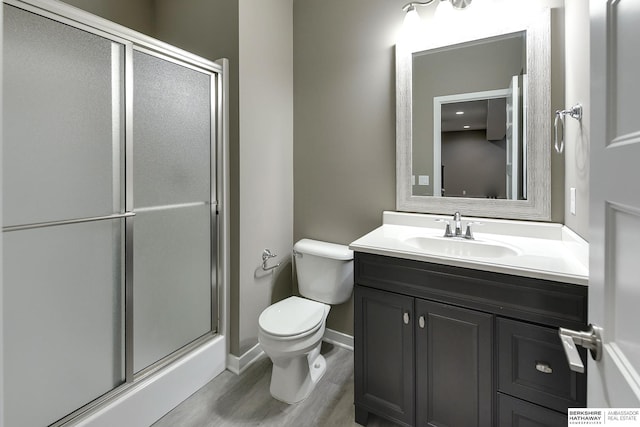 bathroom featuring hardwood / wood-style floors, vanity, an enclosed shower, and toilet