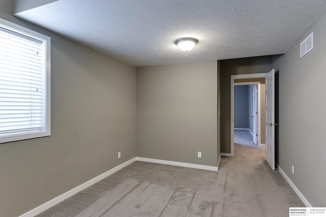 carpeted spare room with a textured ceiling