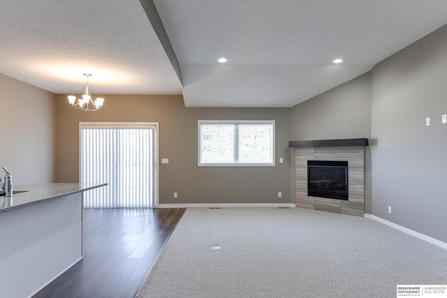 unfurnished living room featuring a notable chandelier, dark hardwood / wood-style flooring, sink, and a tiled fireplace