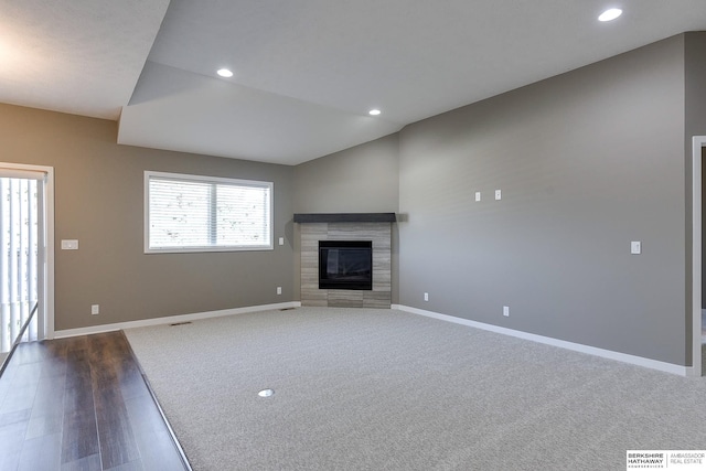 unfurnished living room featuring dark wood-type flooring, a tile fireplace, and vaulted ceiling