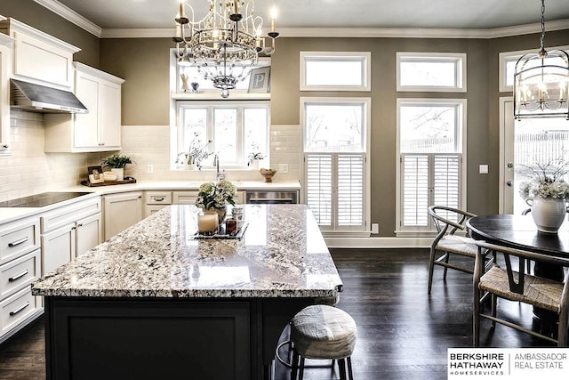 kitchen featuring ventilation hood, a kitchen island, black electric cooktop, and a wealth of natural light