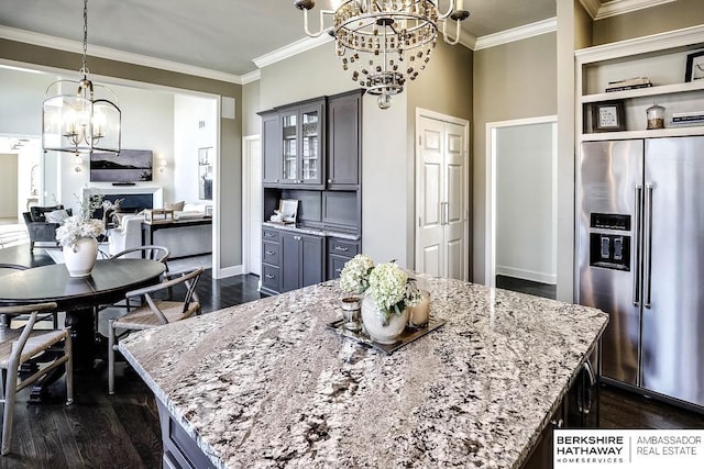 kitchen featuring light stone countertops, stainless steel fridge with ice dispenser, dark hardwood / wood-style flooring, and a kitchen island