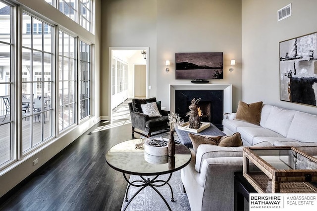 living room featuring dark hardwood / wood-style flooring, a high ceiling, and a high end fireplace