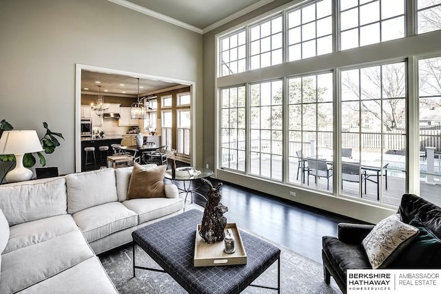 living room with a towering ceiling, crown molding, a wealth of natural light, and a notable chandelier