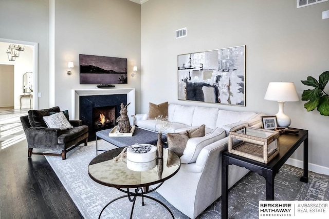 living room with a premium fireplace, hardwood / wood-style floors, and a towering ceiling