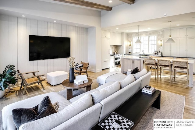 living room featuring beam ceiling and light hardwood / wood-style flooring