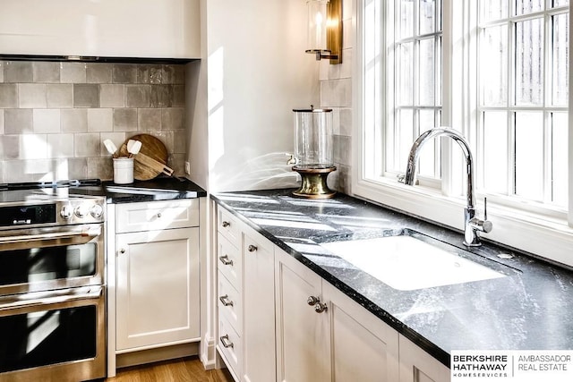 kitchen with white cabinets, tasteful backsplash, sink, and light hardwood / wood-style flooring