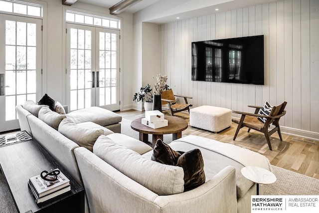 living room featuring french doors, light wood-type flooring, plenty of natural light, and wooden walls