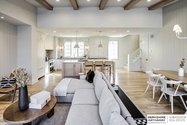 living room with beam ceiling, light wood-type flooring, and wooden walls