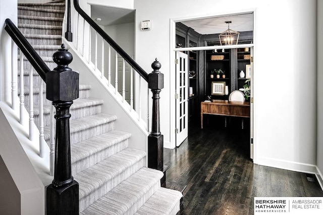 stairway with wood-type flooring and a chandelier