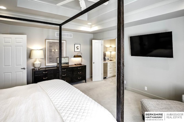 bedroom with ensuite bathroom, ornamental molding, light colored carpet, a tray ceiling, and ceiling fan