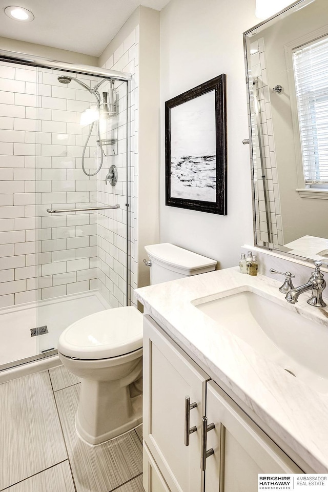 bathroom with tile patterned floors, vanity, a shower with shower door, and toilet