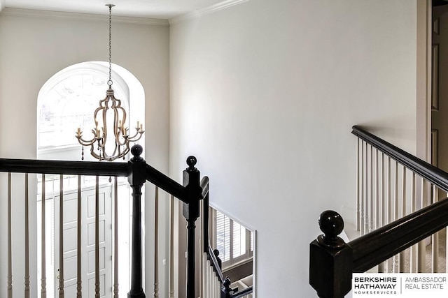 stairs featuring crown molding and a chandelier