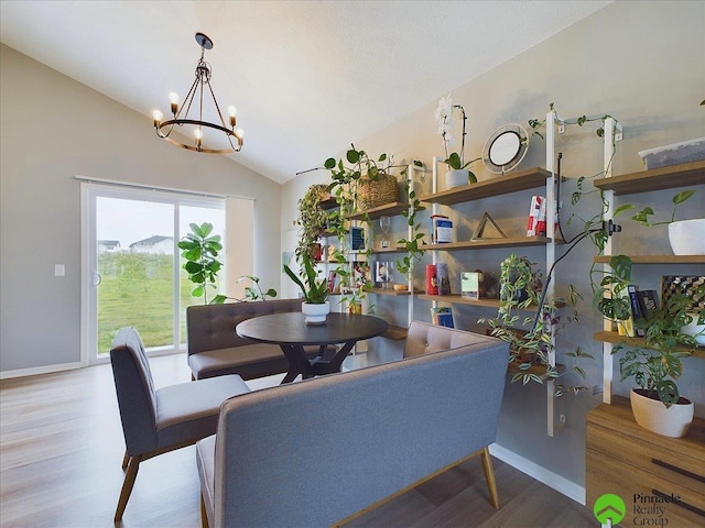 dining space featuring a chandelier, lofted ceiling, baseboards, and wood finished floors