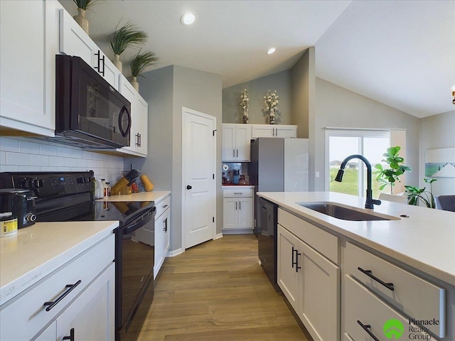 kitchen with a sink, black appliances, white cabinets, and light countertops