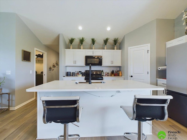 kitchen featuring a breakfast bar area, a kitchen island with sink, and black appliances