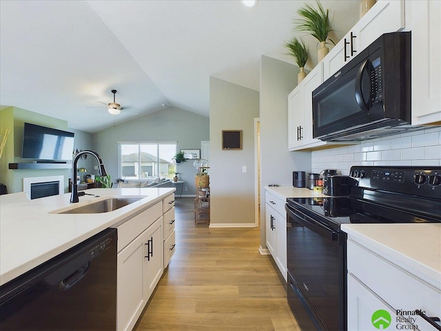 kitchen featuring vaulted ceiling, open floor plan, black appliances, and a sink