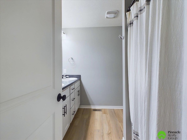 bathroom with visible vents, baseboards, wood finished floors, and vanity