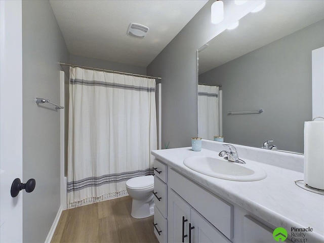 full bathroom with vanity, a shower with shower curtain, wood finished floors, visible vents, and toilet